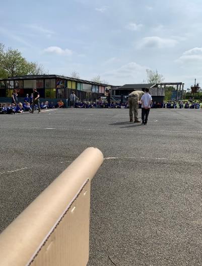 School children and personnel in playground ready to launch paper aircraft models.